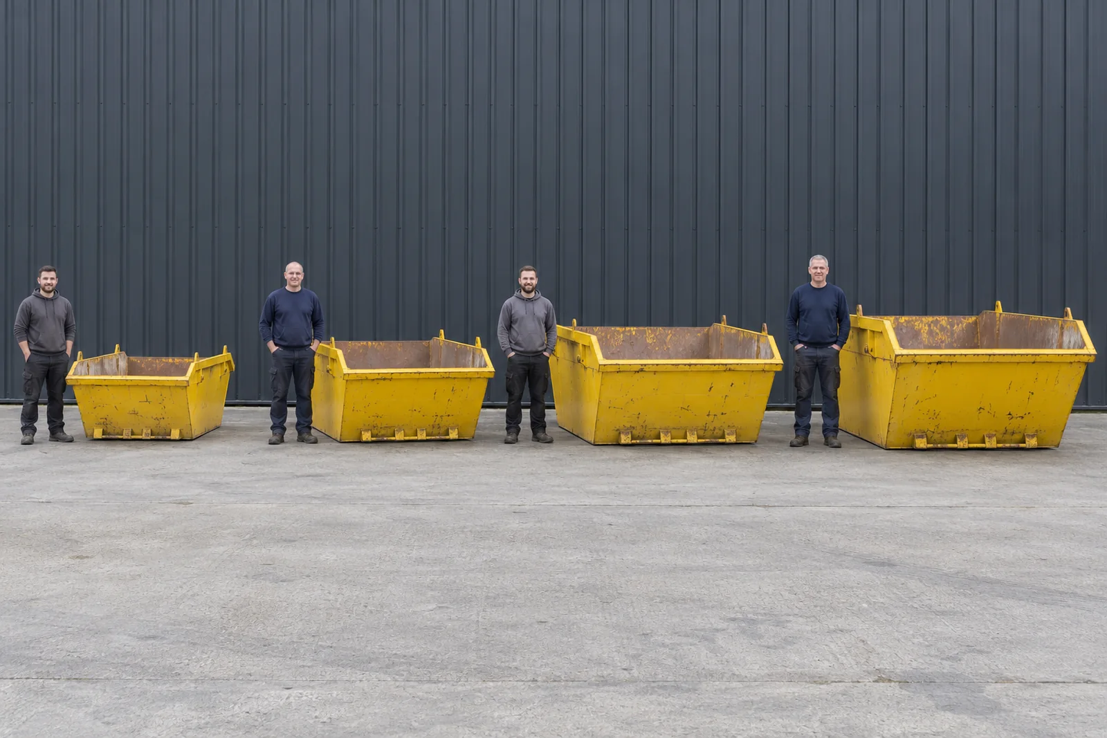 Four yellow skips in increasing sizes with full standing adult scale